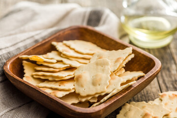 A crispy salted crackers in bowl on wooden table.