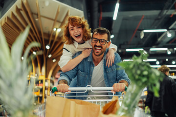 Happy couple having fun while grocery shopping in supermarket