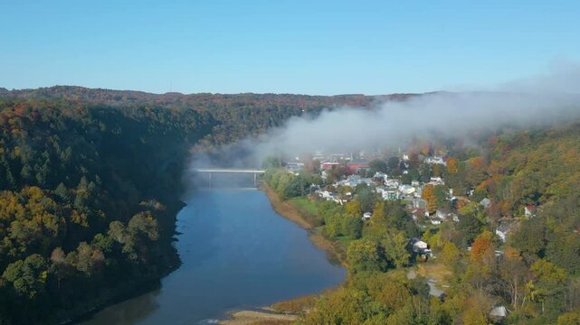 Aerial view of a small town on the mountainside with beautiful Fall foliage and fog, drone 4K