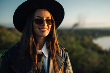 Fototapeta premium Stylish businesswoman smiling outdoors wearing sunglasses and hat