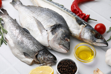 Sea food. Different types of raw fish and products on white tiled table, closeup