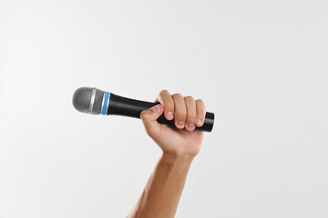 Man with microphone on light grey background, closeup