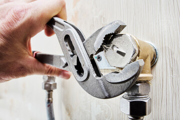 Installing plug on elbow fitting of mixer tap mounting bracket using an adjustable wrench.