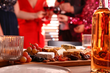 People clinking glasses of wine at party, focus on table with snacks