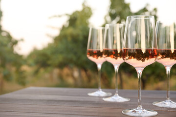 Tasty wine in glasses on wooden table outdoors, closeup. Space for text