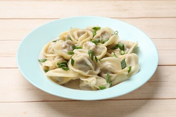 Delicious pelmeni with green onion on white wooden table