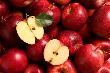 Fresh ripe red apples and green leaves as background, closeup