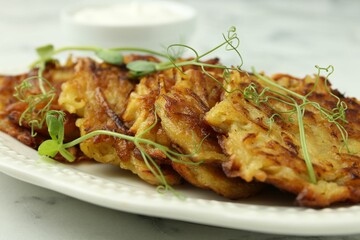 Delicious potato pancakes with fresh microgreens on white marble table, closeup