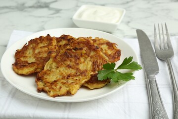 Delicious potato pancakes served on white marble table, closeup