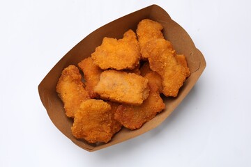 Delicious chicken nuggets in carton box on white background, top view