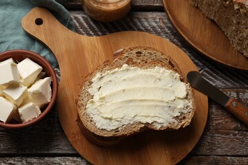 Fresh bread with butter and knife on wooden table, flat lay
