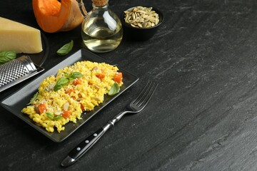 Delicious pumpkin risotto served on black table. Space for text