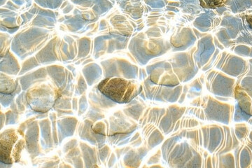 Shimmering riverbed texture, smooth pebbles under clear water with dynamic light refraction patterns
