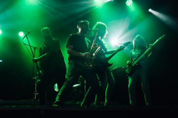 Rock band performing live on stage with green lighting