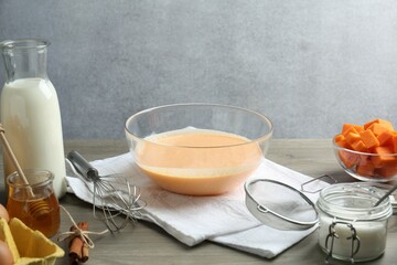 Bowl with dough and ingredients for pumpkin pancakes on wooden table
