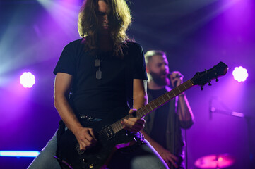 Fototapeta premium Guitarist performing live on stage with purple lighting