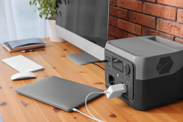 Devices charging from portable power station on wooden desk indoors