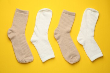 Different soft socks on yellow background, flat lay