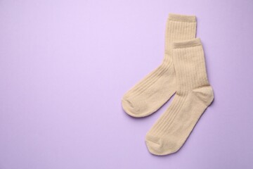 Pair of soft socks on violet background, top view. Space for text