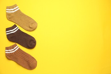 Different soft socks on yellow background, flat lay. Space for text