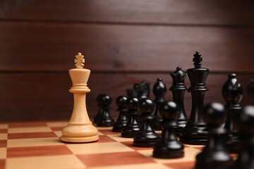 White king in front of other chess pieces on chessboard. Competition concept