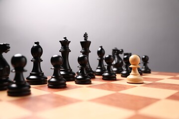White pawn in front of black ones on chessboard. Competition concept