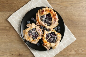 Tasty puff pastries with blueberries on wooden table, top view