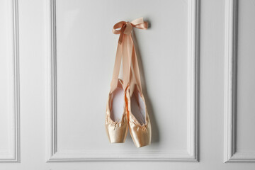 Pair of beautiful pointe shoes hanging on white wall