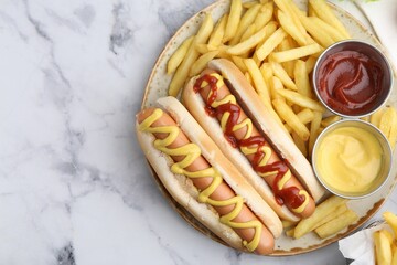 Tasty hot dogs with fries served on white marble table, top view. Space for text