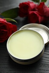 Natural solid perfume and roses on black wooden table, closeup