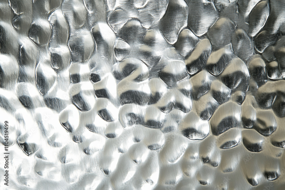 Aufkleber a hammered silver surface with irregular dimples and a reflective sheen, creating a unique handcraft