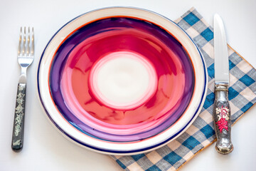 Colorful Empty plate isolated on white background with rustic cutlery set next to it