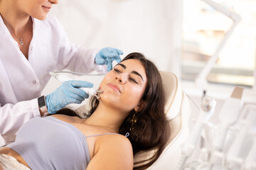 Attractive young girl undergoing radiofrequency skin tightening procedure enhancing facial skin tone and preventing wrinkles. Modern technologies in cosmetology and aesthetic medicine