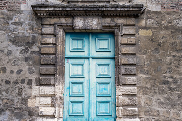 Blue wood old pannelled door in a stone wall