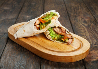 Mexican restaurant fast food - wrapped burritos with chicken and vegetables closeup at wooden desk on table