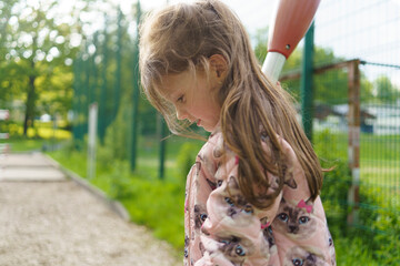 Little cute girl with long hair on playground in summer. Healthy active cheerful child concept
