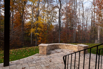 A serene backyard featuring a curved stone patio surrounded by vibrant autumn foliage, creating a peaceful outdoor space ideal for relaxation and nature appreciation.
