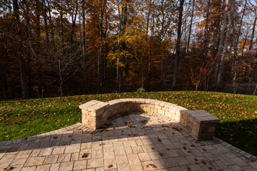 A serene backyard featuring a curved stone patio surrounded by vibrant autumn foliage, creating a peaceful outdoor space ideal for relaxation and nature appreciation.