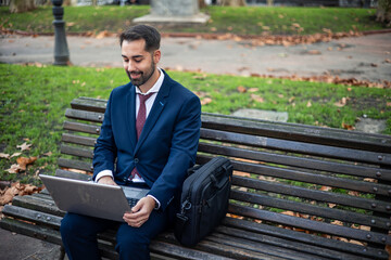 copyspace businessman sitting on a park bench working on his laptop