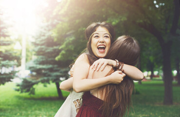 Two happy young girls hug each other. Females embracing, laughing and excited. Woman friendship,...