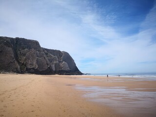 A vibrant beach scene under a bright blue sky with scattered clouds