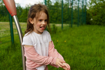 Little cute girl with long hair on playground in summer. Healthy active cheerful child concept