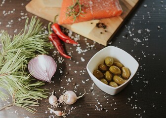 Fresh red salmon on a wooden tray with pepper, salt, garlic, red onion, red pepper, olives with jam