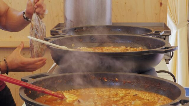 Chef Cooking traditional Spanish Paella on a stove, food festival in barcelona spain. Chef cooking food on fire from mussels, shrimp, squid rice, Catalan catalonian cuisine, street food truck.