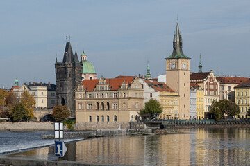 Fototapeta premium Autumn cityscape of Prague with a view of the Old Town. Gothic-style historic buildings are reflected in the Vltava River's calm waters.