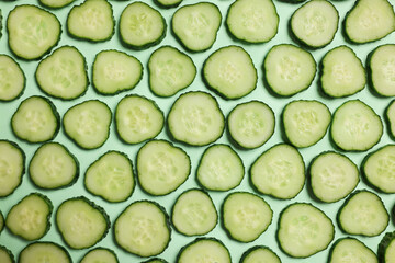 Slices of fresh cucumbers on turquoise background, flat lay