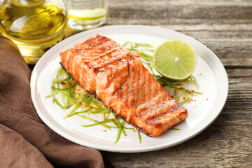 Delicious grilled salmon fillet served on wooden table, closeup