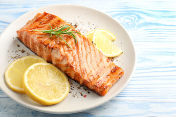 Delicious grilled salmon fillet served on light blue wooden table, closeup