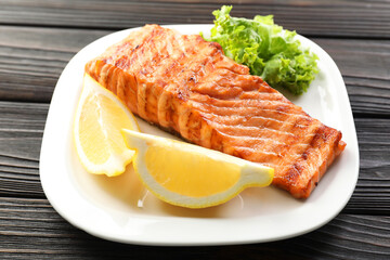 Delicious grilled salmon fillet served on wooden table, closeup