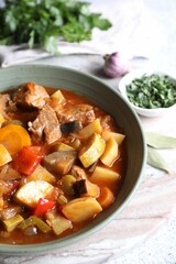 Delicious stew with vegetables in bowl and spices on table, closeup